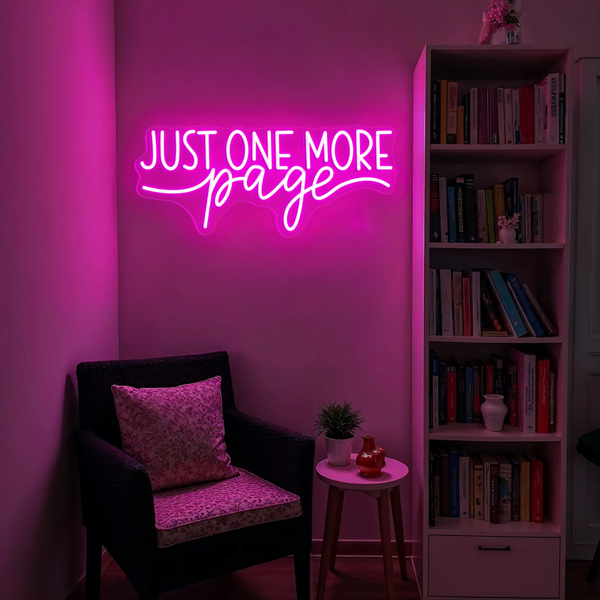Just One More Page neon sign glowing warm white and yellow on a wooden bookshelf in a cozy home library