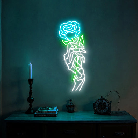 Skeleton hand holding a red rose neon sign glowing on a dark wall above gothic shelf decor