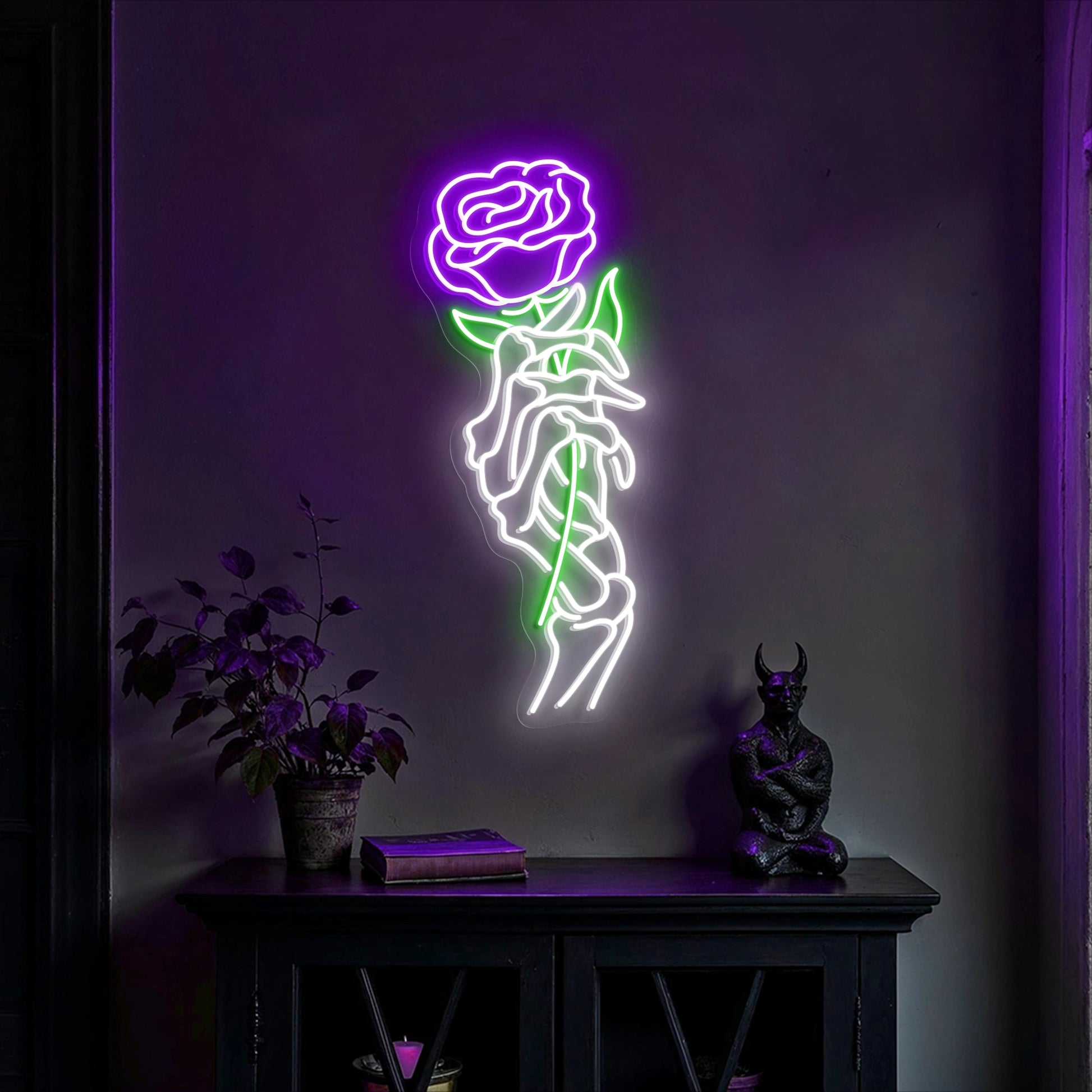 Skeleton hand holding a red rose neon sign glowing on a dark wall above gothic shelf decor